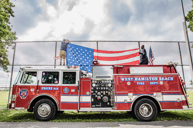 Sideview of Engine 946 and members standing on top putting up an American Flag
