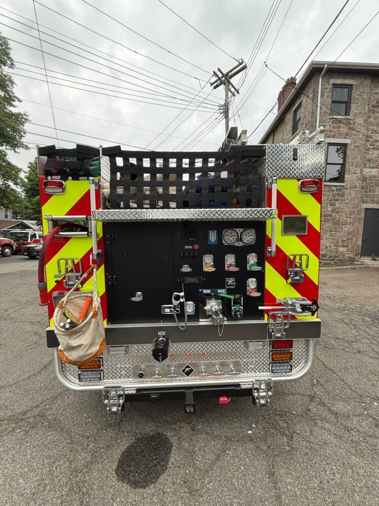 Rear of Edgewater Park Engine 4 with pump gauges, valves, hose bed, and red-and-yellow chevrons.