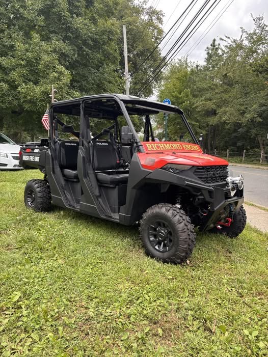 Black and red Richmond Engine Company No. 1 Polaris utility terrain vehicle parked on grass.